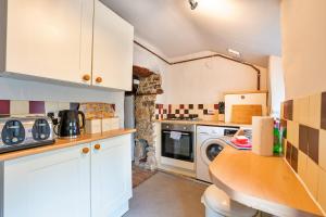 a kitchen with white cabinets and a washer and dryer at Finest Retreats - Westcote Cottage in Bradwell