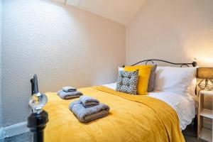 a bedroom with a yellow bed with towels on it at Finest Retreats - Westcote Cottage in Bradwell