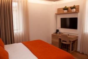 a hotel room with a bed and a desk with a television at Coração do Tua Hotel in Mirandela