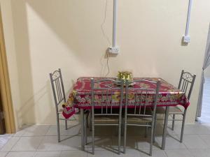 a dining room table with four chairs and a red table cloth at iena homestay in Kampong Bongaliu