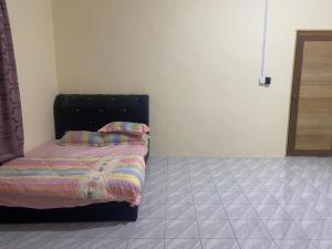 Schlafzimmer mit einem Bett mit einem schwarzen Kopfteil in der Unterkunft iena homestay in Kampong Bongaliu