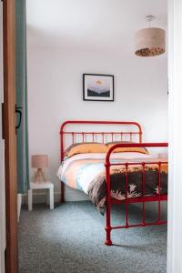 a bedroom with a red metal bed in a room at Albion Cottage central Falmouth with parking and 10 minutes to the beach in Falmouth