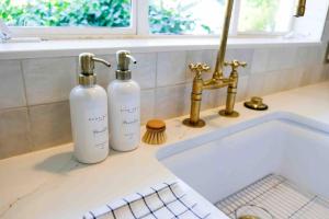 duas garrafas sentadas num balcão ao lado de um lavatório em Cozy Renovated Vintage Modern House Downtown! em Fort Myers