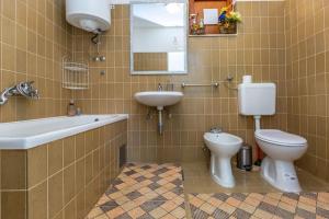 ein Badezimmer mit einem Waschbecken, einem WC, einer Badewanne und einem Spiegel in der Unterkunft Delux Sandy Beach (Duće) in Duće