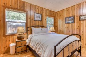 a bedroom with wooden walls and a bed with a white bedspread at Papa Bear Cabin in Welches