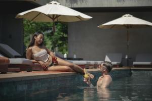 a woman and a boy sitting in a swimming pool at Amber Kampot in Kampot