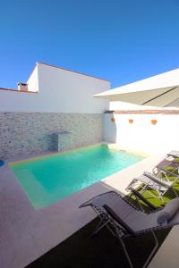a swimming pool with two lounge chairs and a house at Casa do Marquês in Vidigueira