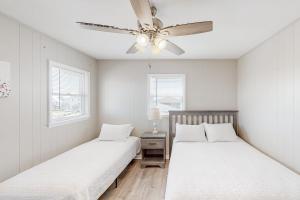 two beds in a bedroom with a ceiling fan at HB261 Rosie's Rendezvous in Holden Beach