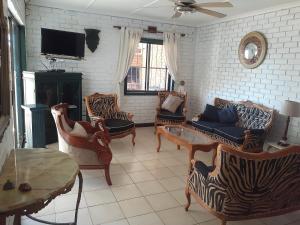 a living room with chairs and a couch and a tv at Turtleshaven in St Lucia