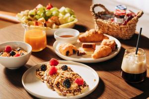 - une table avec des assiettes de nourriture pour le petit-déjeuner et une corbeille de fruits dans l'établissement Cama Luxury Suites, à Athènes