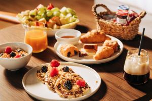 a table with plates of breakfast food and a basket of fruit at Cama Luxury Suites in Athens