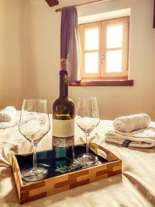 Una botella de vino y dos copas en una cama. en Boutique Rooms & Winery Žorž en Vipava