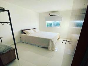 a white bedroom with a bed and a window at Apartamento na Massagueira, 3km Praia do Francês in Marechal Deodoro
