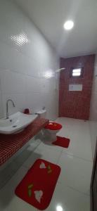 La salle de bains est pourvue d'un lavabo, de toilettes et de tapis rouges. dans l'établissement Casa Viva Milagres, PX ao Réveillon dos Milagres, à São Miguel dos Milagres