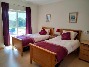 two beds in a room with a window at Prestige for Home - Moradia Vista Mar, Piscina, Jardim e Estacionamento in Nora