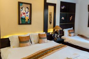 a bedroom with two beds and a painting on the wall at Pai Residence Hotel in Chiang Mai