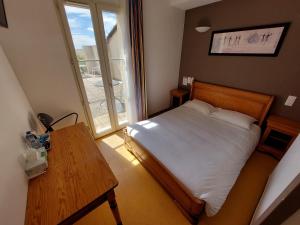 1 dormitorio con cama, mesa y ventana en Logis - Le relais des deux vallées, en Salvagnac