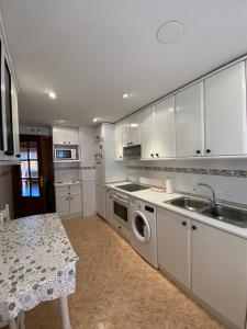 a kitchen with white cabinets and a sink and a table at Las Golondrinas in Soria