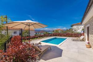 a patio with an umbrella and a swimming pool at Holiday house VILLA ANDRO in Pinezici