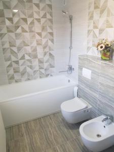 a white bathroom with a toilet and a sink at Kiki's Villa in Chişinău