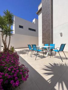 patio z krzesłami, stołem i kwiatami w obiekcie Villa Mil Palmeras w mieście Campoamor