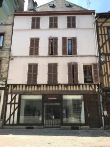 a large white building with brown shuttered windows at Une Nuit Comme Un Chevalier! Coeur historique - Hypercentre. in Troyes
