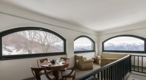 a room with three windows and a table and chairs at Il Larice - Agriturismo Alpe del Ville San Primo by Wonderful Italy in Bellagio