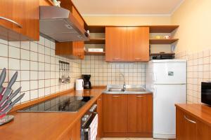 a kitchen with wooden cabinets and a white refrigerator at Apartment Blazi Njivice in Njivice
