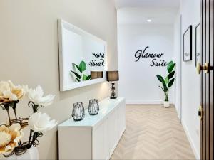 a white hallway with flowers and a mirror at Glamour Suite Cagliari in Cagliari