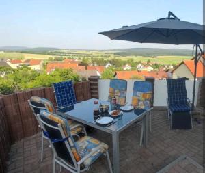 a table and chairs on a patio with an umbrella at Ferienwohnung Look wide in Oberelsbach