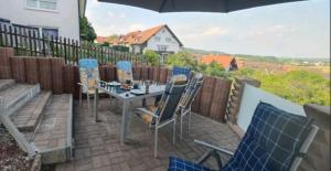 un patio con sillas, una mesa y una sombrilla en Ferienwohnung Look wide, en Oberelsbach