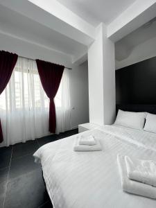 Schlafzimmer mit einem großen weißen Bett und roten Vorhängen in der Unterkunft Marvellous Aparthotel with Master Apartments Suceava in Suceava