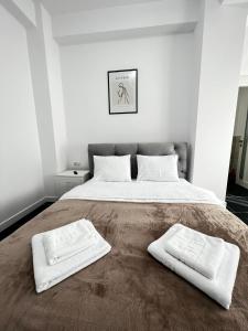 a bedroom with a large bed with two white towels on it at Marvellous Aparthotel with Master Apartments Suceava in Suceava