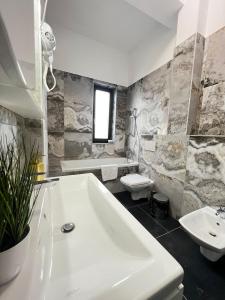 łazienka z wanną, toaletą i umywalką w obiekcie Marvellous Aparthotel with Master Apartments Suceava w Suczawie