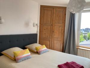 a bedroom with a bed with two pillows and a window at L'escale Granvillaise in Granville