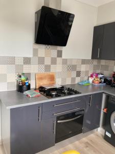 a kitchen with a stove and a tv on the wall at L'escale Granvillaise in Granville