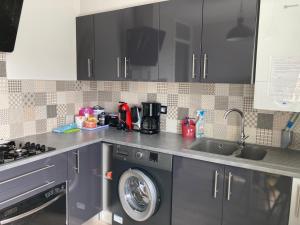 a kitchen with a washing machine and a sink at L'escale Granvillaise in Granville