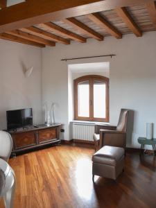 un soggiorno con TV, divano e sedia di Cora Aparthotel Stradivari a CastellʼArquato