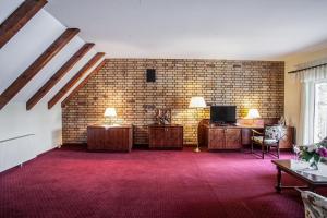 a living room with a brick wall and a tv at Waldsee Hotel am Wirchensee in Treppeln