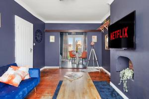 ein Wohnzimmer mit einem blauen Sofa und einem TV in der Unterkunft Home at The Brent in Dartford