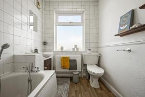 a bathroom with a tub and a toilet and a sink at Home at The Brent in Dartford