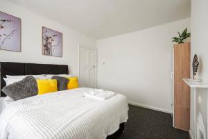ein Schlafzimmer mit einem weißen Bett mit gelben und grauen Kissen in der Unterkunft Home at The Brent in Dartford