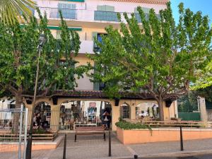 un bâtiment avec des arbres et des bancs devant lui dans l'établissement Le Best à Cassis,Top emplacement,Parking,double balcon, à Cassis