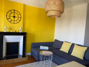 a living room with a blue couch and a clock at L'escale Granvillaise in Granville
