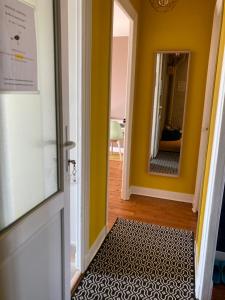 a hallway with yellow walls and a door with a rug at L'escale Granvillaise in Granville