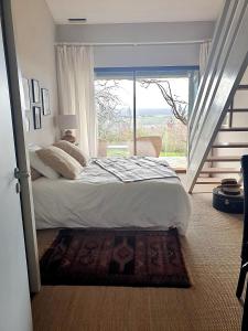 a bedroom with a bed and a large window at Chambres d hotes, la maison de Kat in Lamothe-Capdeville