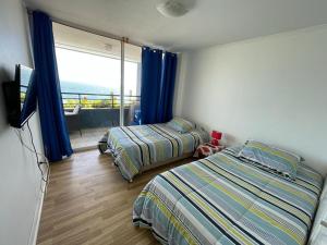 a bedroom with two beds and a television and a balcony at VADIGI COCHOA in Viña del Mar