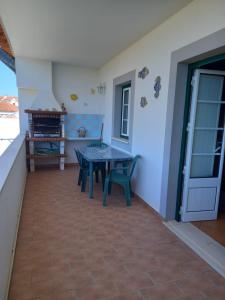 une terrasse avec une table et des chaises dans une maison dans l'établissement T2,Casa Sol e Mar 50464/AL, à Vila Nova de Milfontes