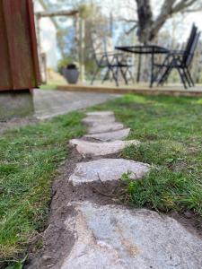 a stone path in the grass next to a table at Mindre lägenhet i en lantlig miljö i Skrea in Falkenberg +2 photos
