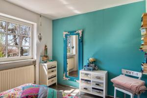 a bedroom with blue walls and a mirror at La Maisonannette in Vinningen